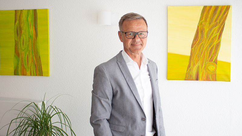 Herr Jeske in der Frontalaufnahme, Hintergrund unscharf, Motiv Ordner