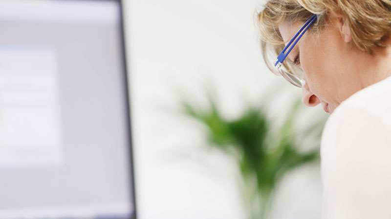 Motiv Finanzbuchhaltung und Jahresabschluss, Mitarbeiterin arbeitet am Computer, unscharfer Bildschirm